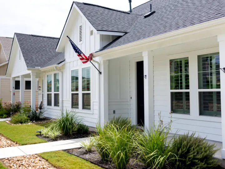 The side of a clean white house with fresh landscaping